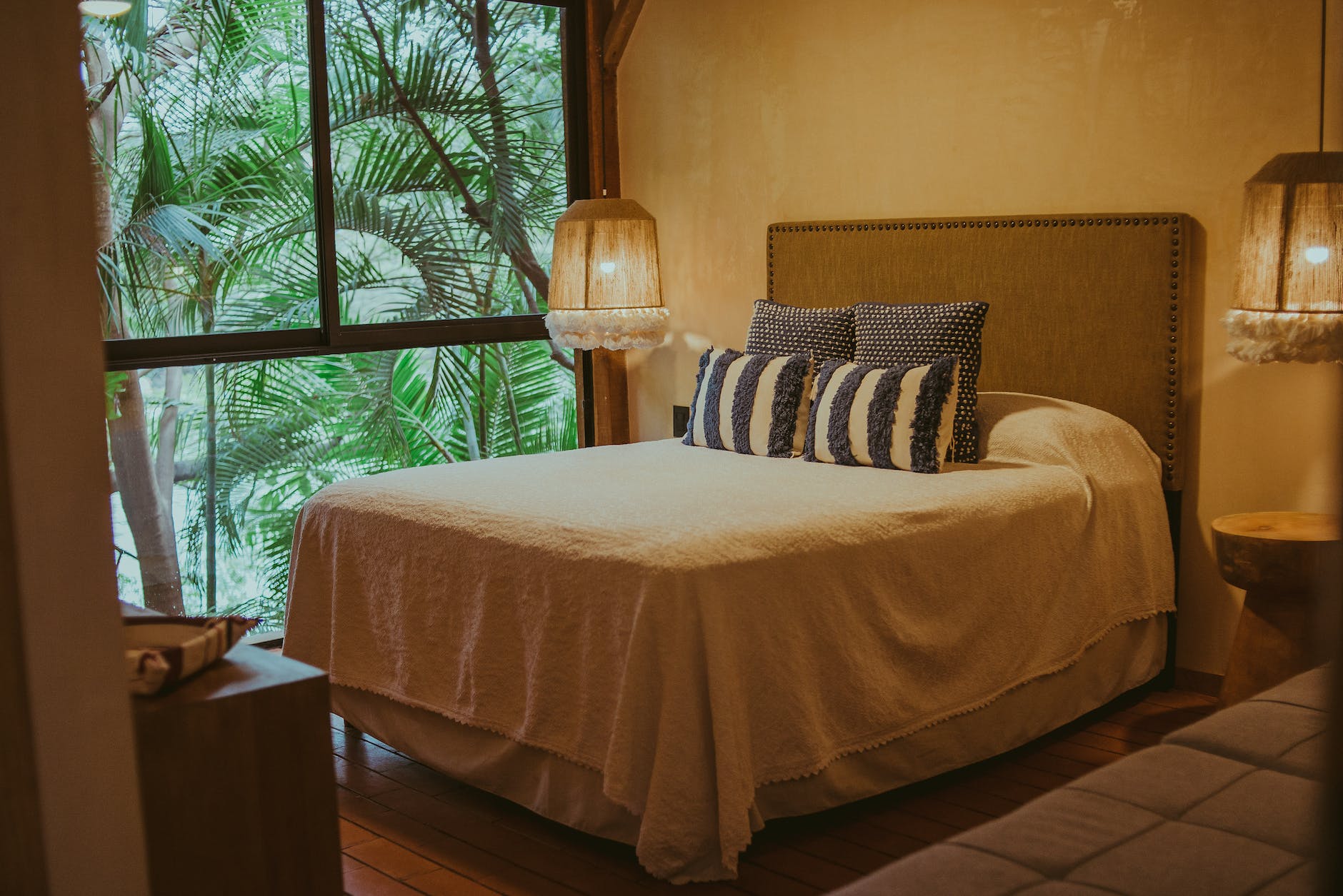 hotel bedroom with palm leaves behind window